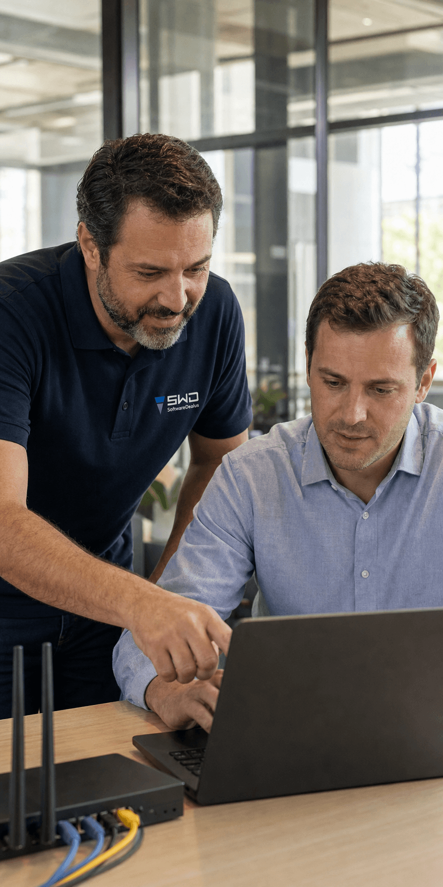 A SoftwareDealus IT professional helping a business employee at a laptop